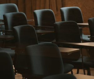 어두운 조명 아래 밀집해 있는 비어 있는 교육용 의자와 책상들, 과열된 사교육 시장과 학부모들의 무거운 교육비 부담 및 사회적 해법 고민을 상징하는 이미지