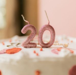 케이크 위에 꽂힌 숫자 20 모양의 분홍색 반짝이 양초, 현대인들이 가장 돌아가고 싶어 하는 시절인 찬란한 20대 청춘과 과거에 대한 그리움을 표현한 모습