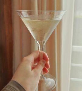 한 손으로 투명한 칵테일 잔을 들고 있는 모습, 술자리에서 우연히 겹지인의 존재를 알게 된 후 친구의 대화나 말 한마디를 조심스럽게 되짚어보는 심리적 긴장감을 표현한 이미지