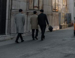 코트를 입고 가방을 든 채 거리를 걸어가는 남성 직장인들의 뒷모습, 출근 시간 엄수와 전통적인 기업 문화를 연상시키는 직장인들의 출근길 풍경