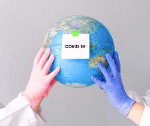COVID 19 문구가 붙은 지구본을 장갑 낀 두 손으로 들고 있는 모습, 코로나 시기 사회적 거리두기로 인해 제사 문화가 축소되거나 생략되었던 배경을 상징하는 이미지