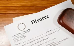 Divorce 문구가 적힌 이혼 서류 종이 위에 놓여 있는 반지 모습, 이혼을 경험한 돌싱들이 과거의 아픔을 딛고 재혼을 신중하게 고민하는 심리적 배경을 상징하는 이미지