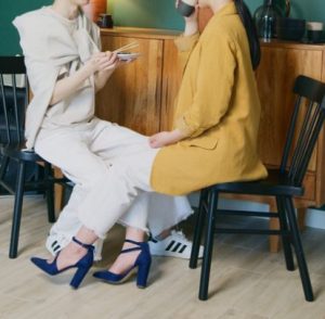 실내 의자에 앉아 음료를 마시며 편안하게 대화를 나누는 두 사람의 모습, 지인에게 선의로 소개팅을 제안하는 일상적인 대화 과정을 상징하는 이미지